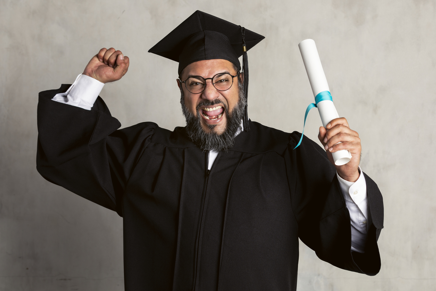 Happy senior man in a graduation gown holding his master's degre
